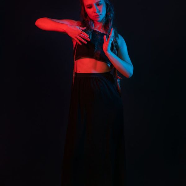 Woman with vibrant energy performing a fluid cardio movement in a dark studio.